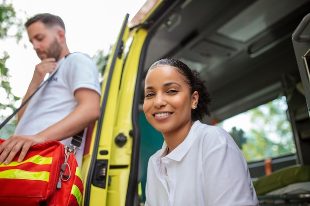 Multi-etnische paramedici staan voor de ambulance Noodarts en verpleegkundige staan voor de ambulance