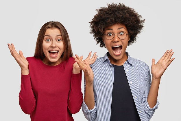 Multiraciale, emotioneel diverse jonge vrouwen grijpen de handen in elkaar, roepen luid, nonchalant gekleed