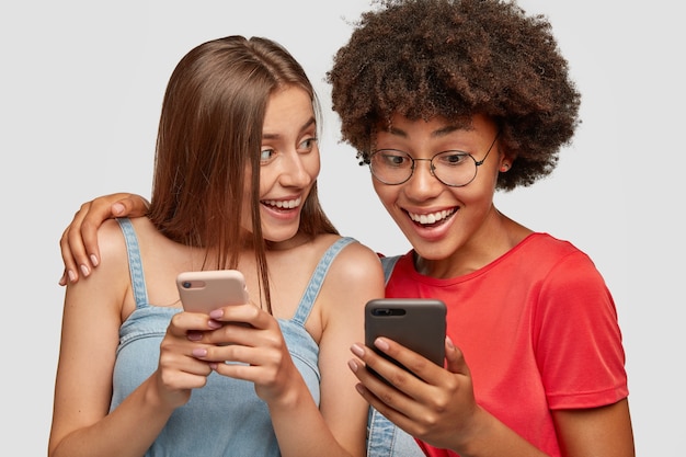 Multiraciale vrienden omarmen en delen multimediabestanden via bluetooth op de mobiele telefoon