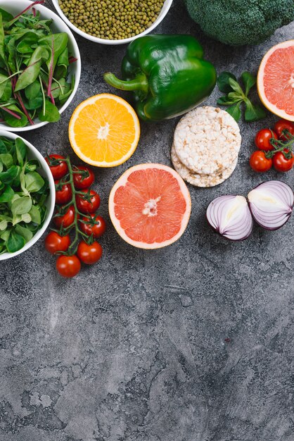 Mungboon; spinazie; citrusvrucht; gepofte rijstwafel en verse groenten op concrete achtergrond