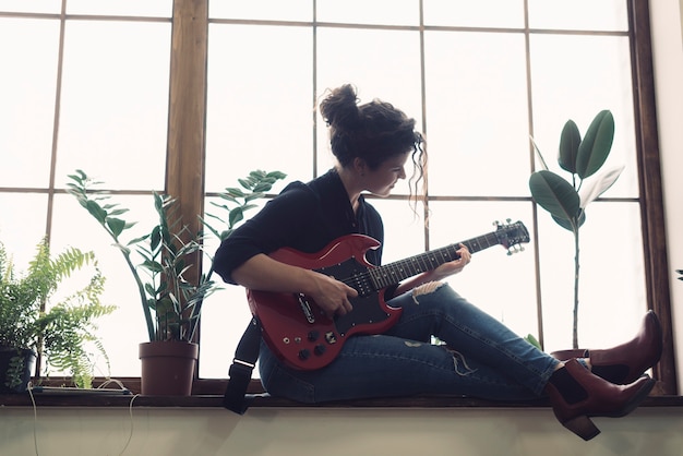 Musicus die op gitaar voor venster speelt