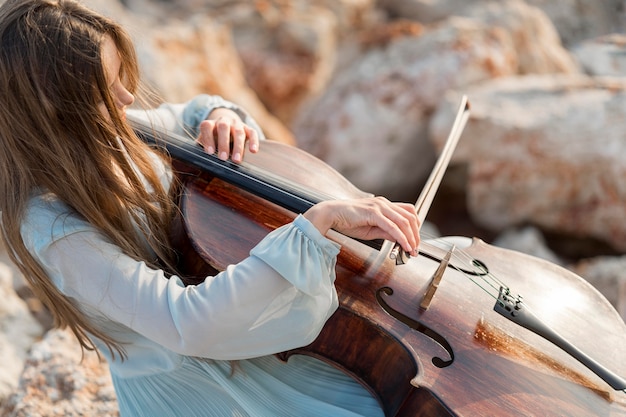 Muzikant die cello op rotsen speelt