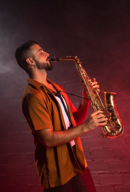Gratis foto muzikant die de saxofoon in mist speelt
