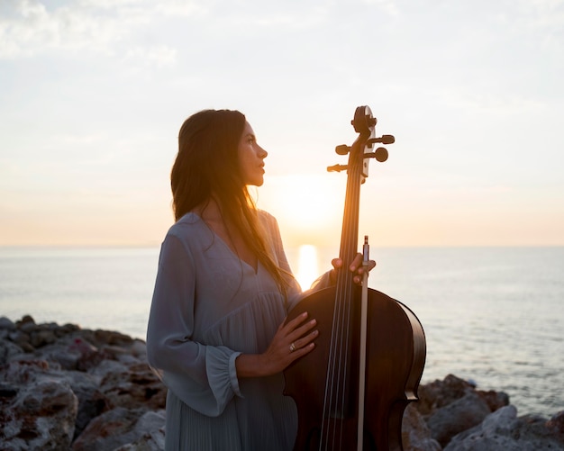 Muzikant met cello buiten bij zonsondergang