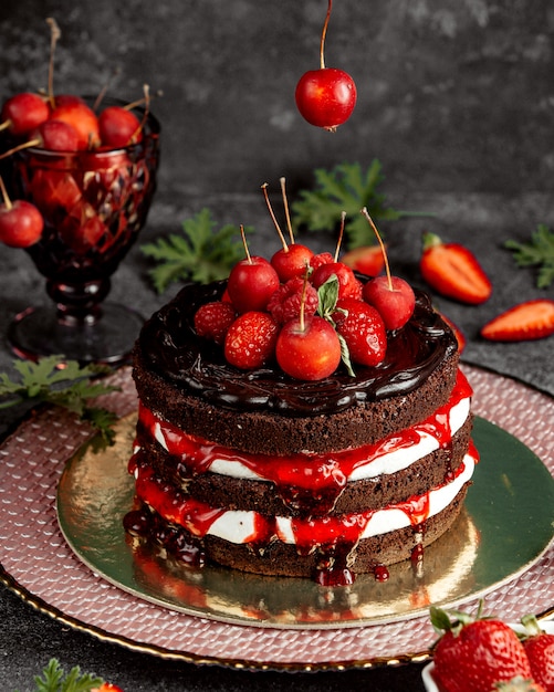 Naakte chocoladetaart versierd met aardbeien, frambozen, appeltjes en siroop