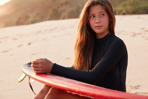 Nadenkend aantrekkelijke jonge vrouw denkt over surfwedstrijd, diep in gedachten zijn