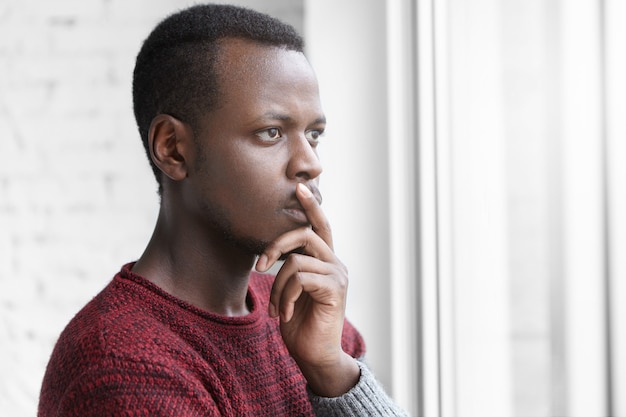 Nadenkend bezorgd Afro-Amerikaanse art director, nonchalant gekleed en de vinger op de lippen houden