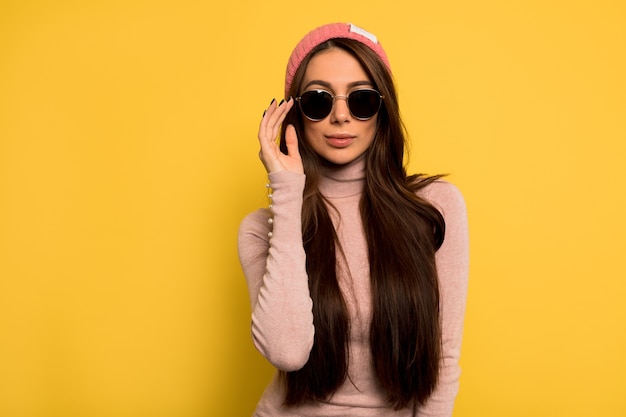 Nadenkend geweldige blanke vrouw met zwarte zonnebril en roze pet. Indoor portret van nieuwsgierige mooie vrouw met lang haar