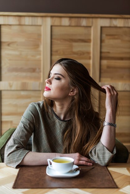 Nadenkend jonge vrouw spelen met haar haren