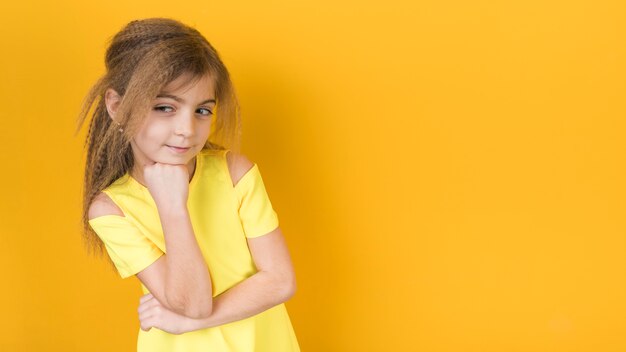 Nadenkend meisje in kleding op gele achtergrond