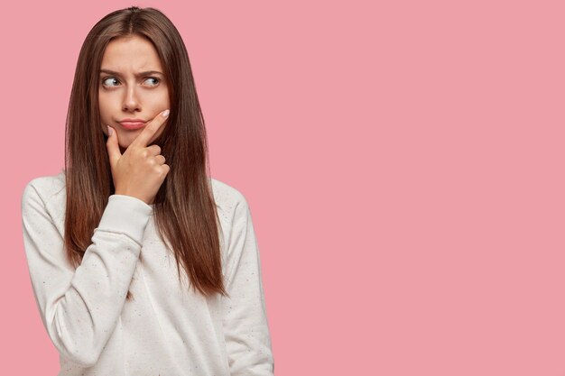 nadenkend mooie brunette poseren tegen de roze muur