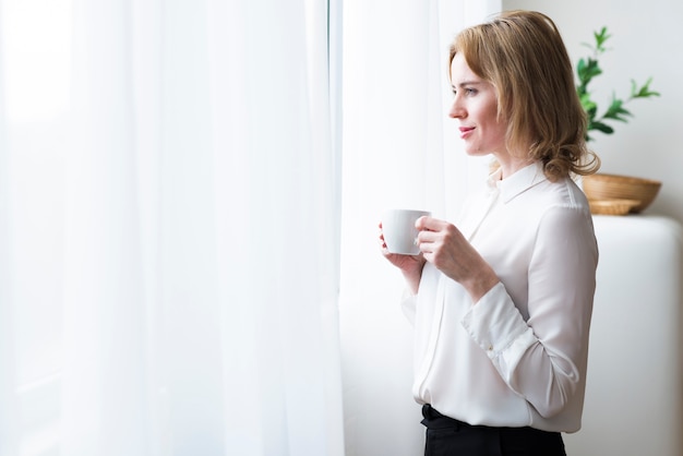 Gratis foto nadenkende bedrijfsvrouw met koffiekop