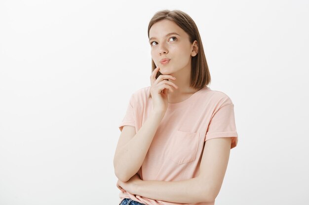 Nadenkende glimlachende vrouw die rechtsboven kijkt, een keuze maakt, besluit welke keuze