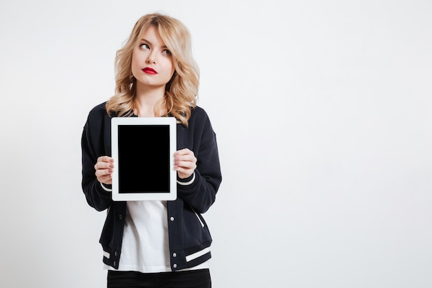 Gratis foto nadenkende jonge dame die vertoning van tablet toont