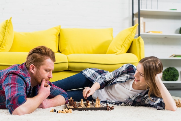 Nadenkende jonge man die glimlachende vrouw bekijkt die het schaakspel speelt