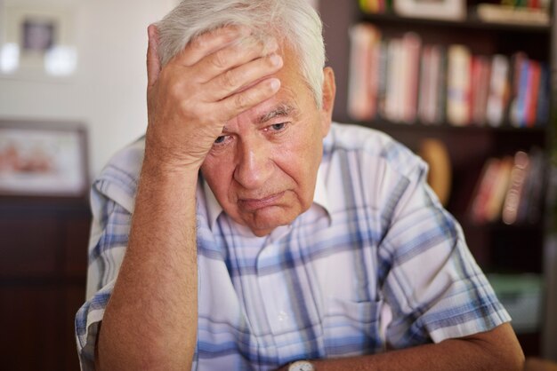 Nadenkende senior man in de woonkamer