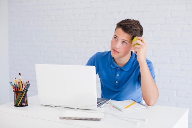 Nadenkende tiener jongen met behulp van laptop