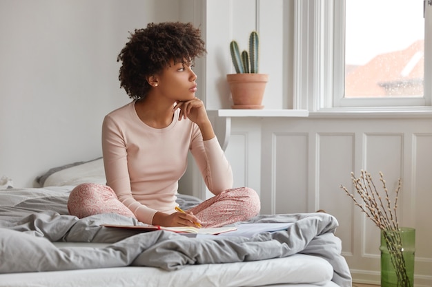 Gratis foto nadenkende vrouw met donkere huid houdt hand onder de kin