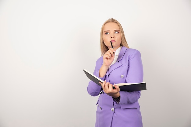 Nadenkende vrouw met geopende tablet en potlood op wit.