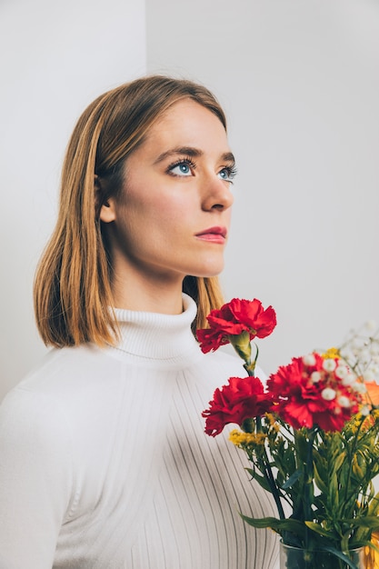 Gratis foto nadenkende vrouw met heldere bloemen