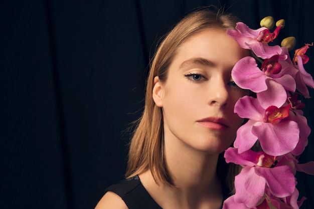 Gratis foto nadenkende vrouw met roze bloem