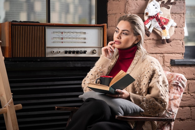 Nadenkende vrouwenzitting met een boek en het drinken van koffie