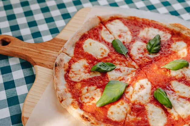 Napolitaanse pizza met ham, kaas, rucola, basilicum, tomaten besprenkeld met kaas