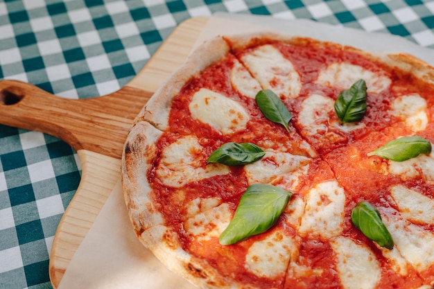 Napolitaanse pizza met ham, kaas, rucola, basilicum, tomaten besprenkeld met kaas