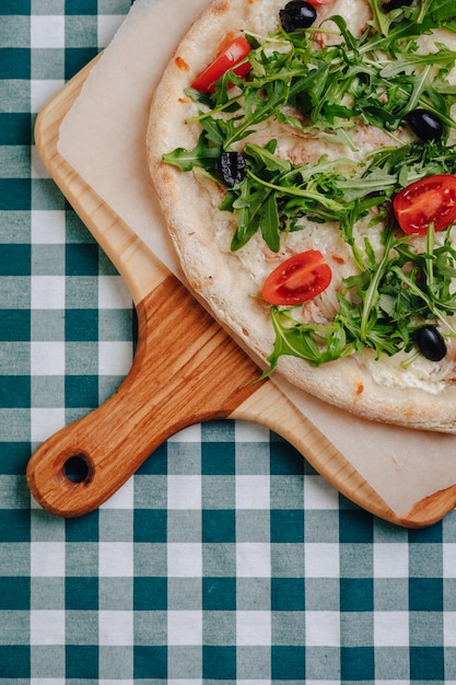 Napolitaanse pizza met tonijn, kaas, rucola, basilicum, tomaten, olijven, bestrooid met kaas