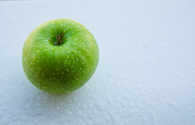 Natte groene appel op witte, hoge hoekmening.