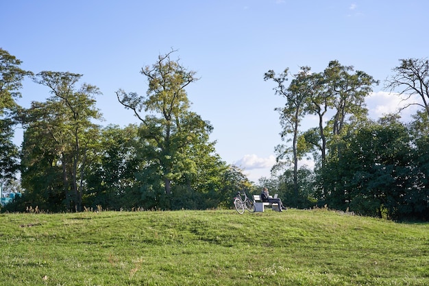 Natuur en landschap mooie zonnige dag in het park vrouw zittend op een bankje en met behulp van haar laptop werken