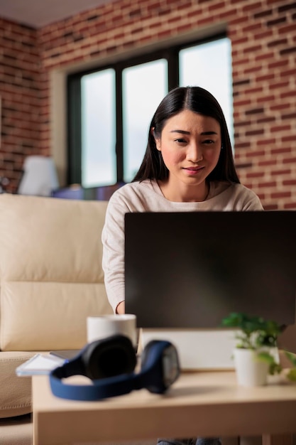 Natuurlijke jonge aziatische vrouw tevreden gelukkig vrolijk schattig mooie freelance zit binnenshuis in het kantoor aan huis met behulp van laptopcomputer werkende webtechnologie online web 3.0 applicatie