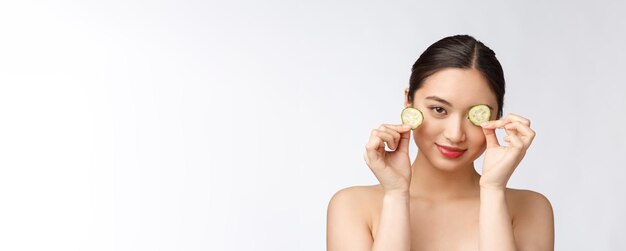 Natuurlijke zelfgemaakte verse komkommer gezichts eye pads gezichtsmaskers Aziatische vrouw met komkommer pads en glimlach ontspannen met natuurlijke zelfgemaakte