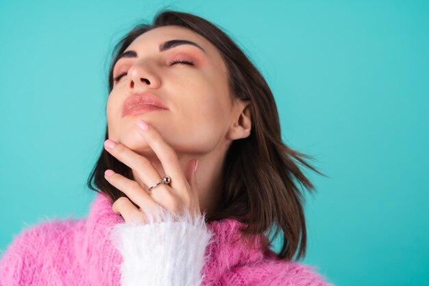 Nauw portret van een jonge vrouw in een trui op blauw met sierlijke handen, lange dunne vingers