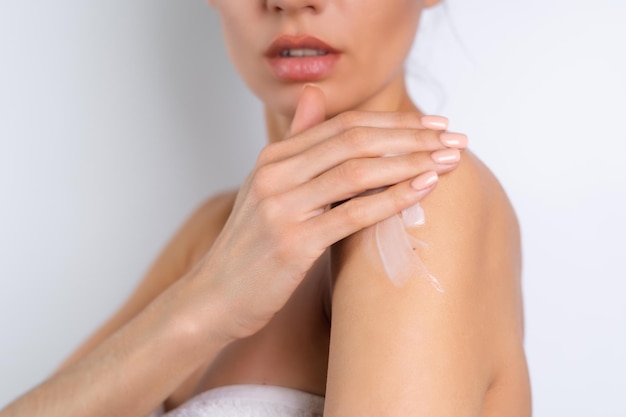 Gratis foto nauwe schoonheidsportret van topless vrouw met perfecte huid met fles shampoolotion van toepassing op schouders en lichaam op witte achtergrond