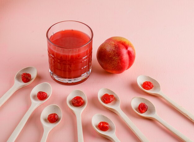 Nectarine met gedroogde kersen, sap op roze oppervlak, hoge hoek bekeken.