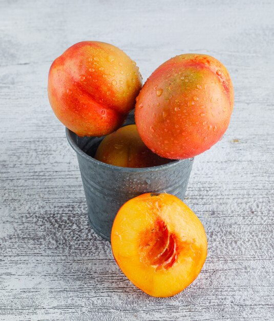 Nectarines in een mini-emmer op grungy grijze oppervlak, hoge hoek bekijken.