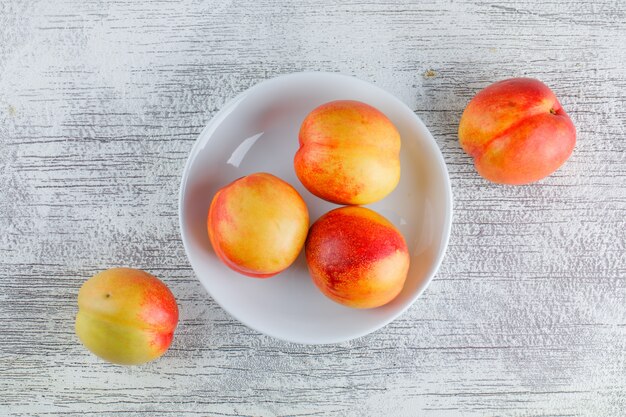 Nectarines in een plaat op een grungy grijze oppervlak. plat lag.