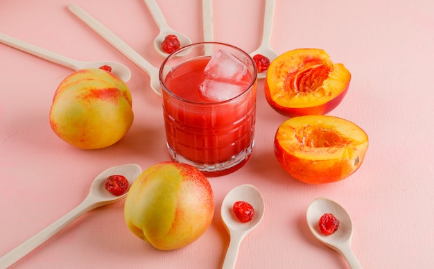 Nectarines met gedroogde kers, sap op roze oppervlak, hoge hoek bekeken.