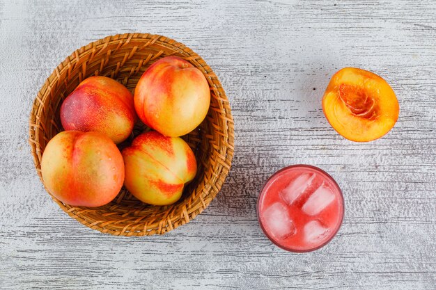 Nectarines met sap in een mand op grungy muur, bovenaanzicht.