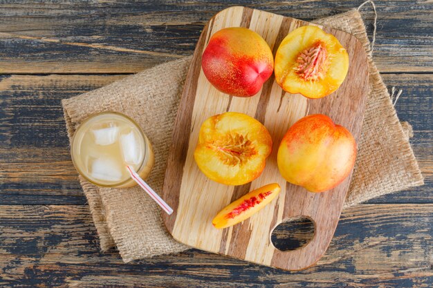 Nectarines met snijplank, sap op houten en stuk zak