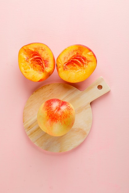 Nectarines op roze en snijplank tafel. plat lag.