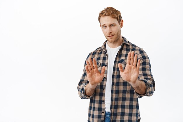 Nee, bedankt Jonge roodharige man die handen schudt om te weigeren aanbod af te wijzen en niet mee eens te zijn stop met dit achterblijven houd afstand over witte achtergrond