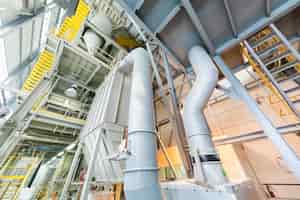 Gratis foto neerwaarts zicht op moderne operationele fabriek met grijze buizen en ladders zware industrie machines metaalbewerking werkplaatsconcept
