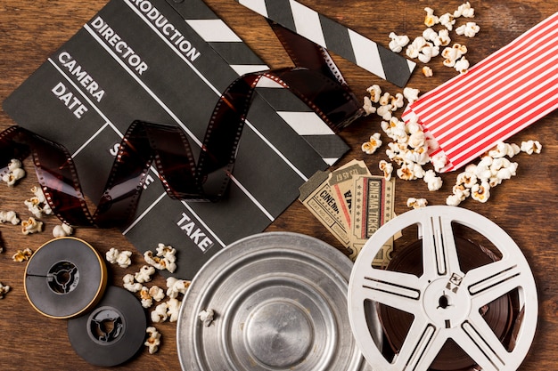 Gratis foto negatieve strepen met filmklapper; filmhaspels; kaartjes en popcorn op houten bureau