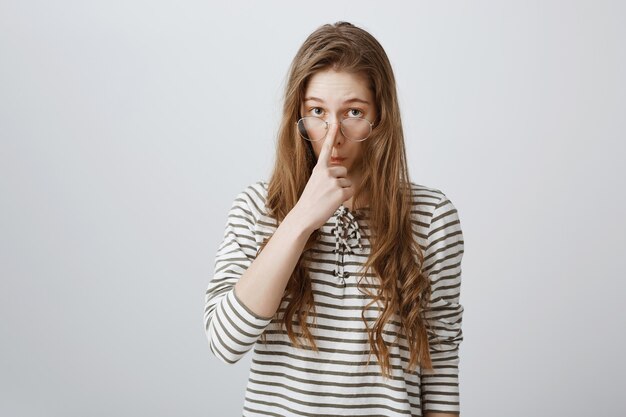 Nerdy slim meisje zet een bril op en ziet er geamuseerd uit