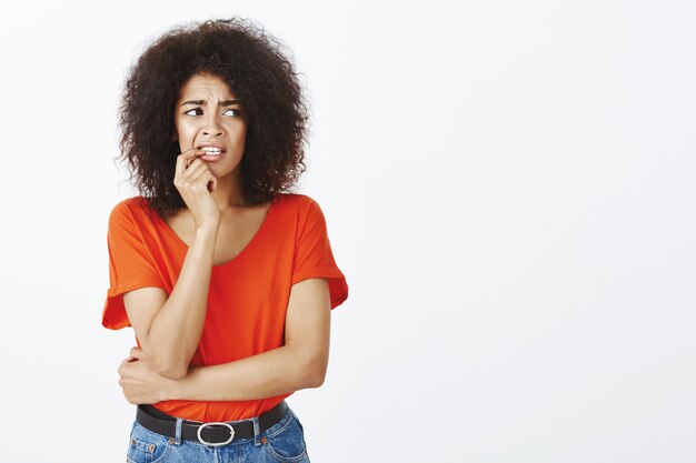 nerveuze vrouw met afro kapsel poseren in de studio