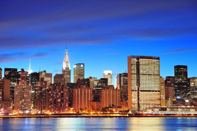 New York City Manhattan midtown panorama in de schemering met wolkenkrabbers verlicht over East River