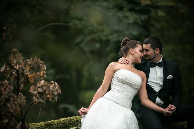 Newlyweds kijken in hun ogen met een bos op de achtergrond