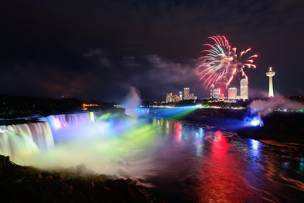 Niagarawatervallen 's nachts verlicht door kleurrijke lichten met vuurwerk